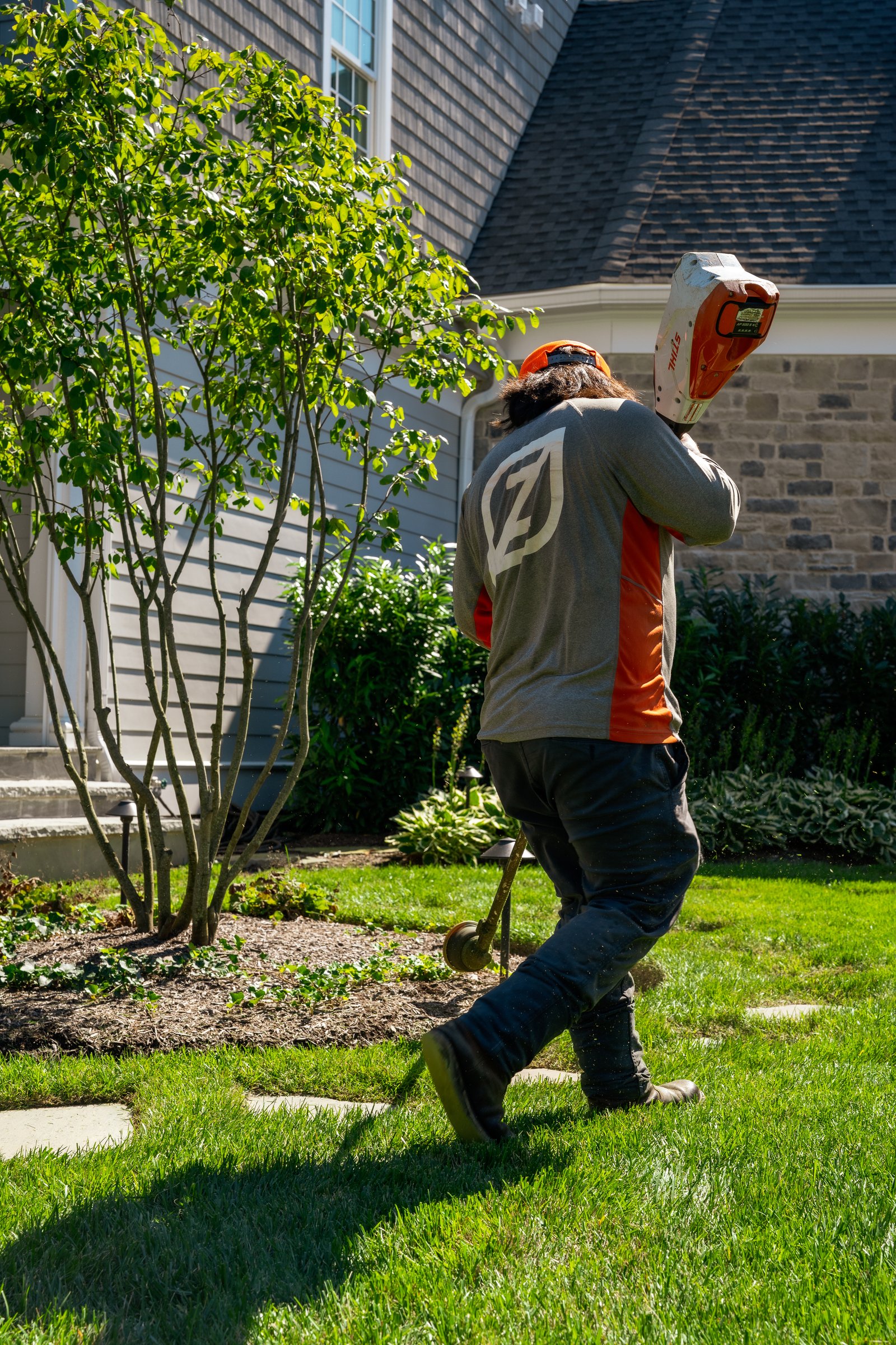 Zeppa's crew member edging a bed line with a string trimmer
