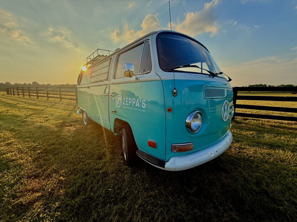 Zeppa's restored 1970s Volkswagen bus at a horse fence at sunset